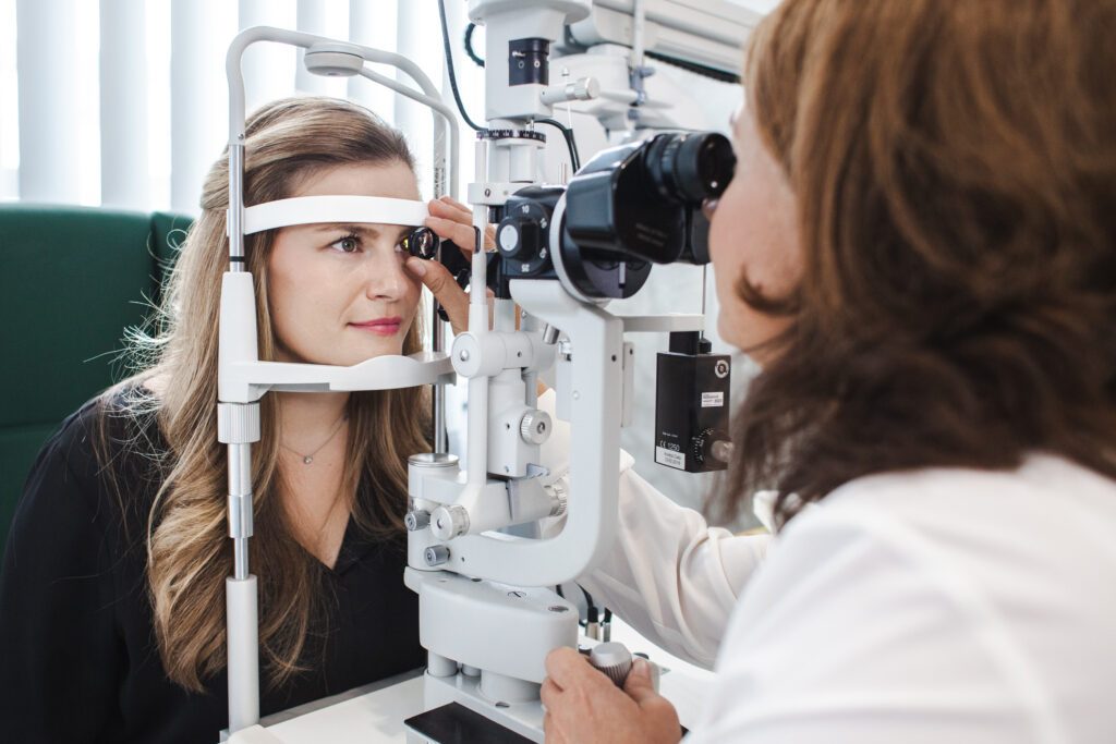 A patient sits in front of the slit lamp and is examined