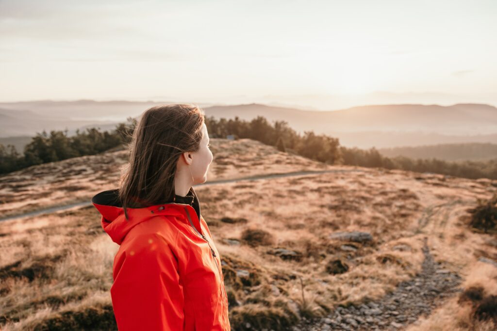 A woman stands on a hill and looks into the distance