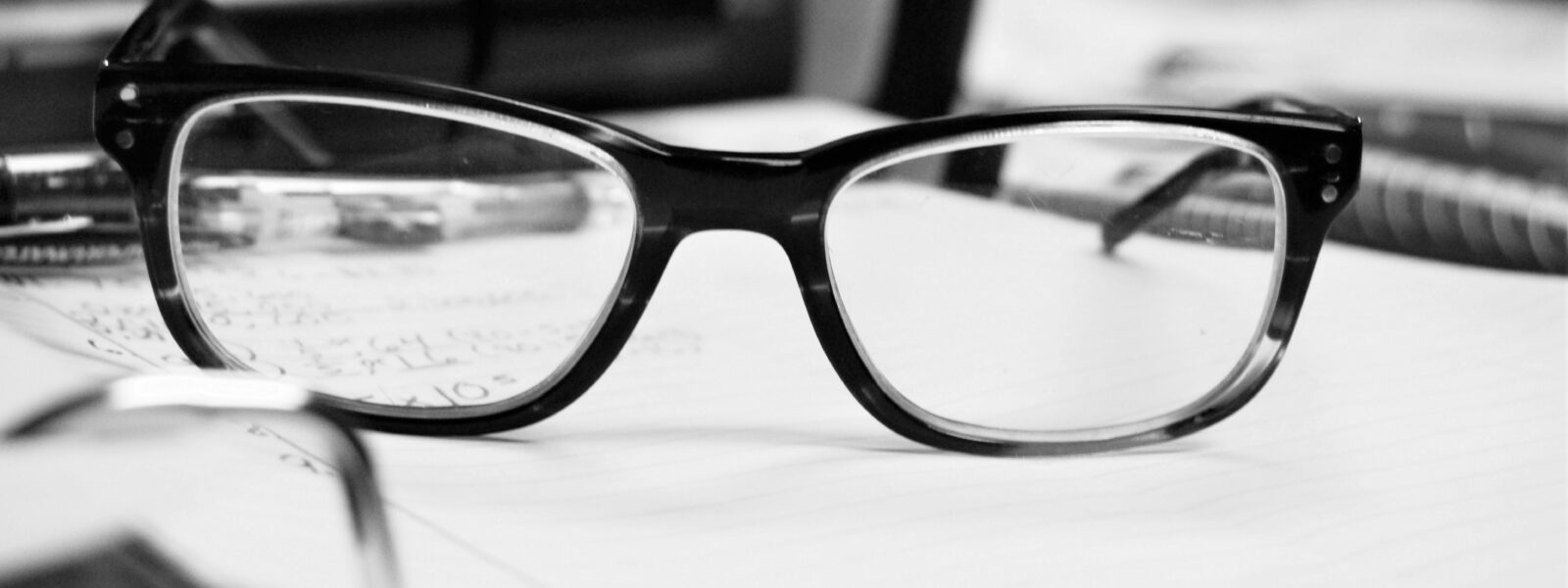 Eine Brille liegt auf einem Buch und zeigt die Sicht eines Menschen mit Hypermetropie